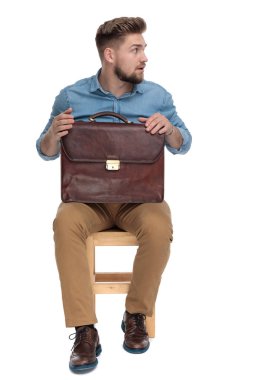 surprised young man looking to side and holding suitcase