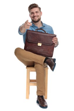 happy young man pointing finger and holding suitcase