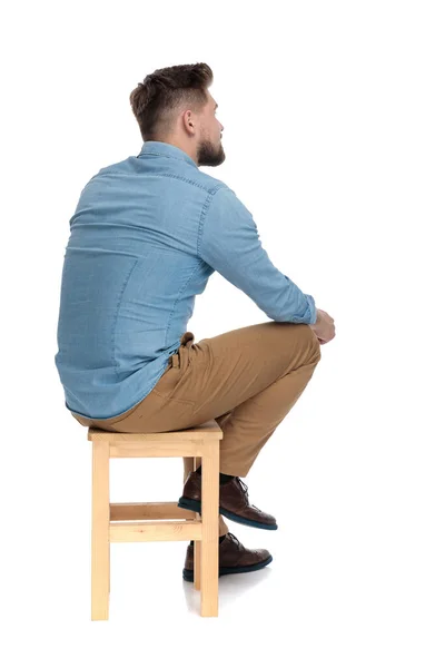 Young casual man in denim shirt sitting and thinking — Stockfoto