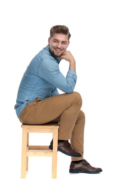 Happy young man in denim shirt smiling and looking to side — Stockfoto