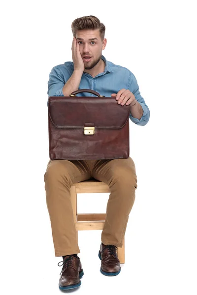 Shocked young man holding suitcase — Stockfoto