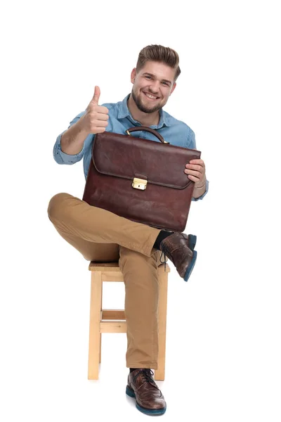 Smiling young guy making thumbs up sign and holding suitcase — Φωτογραφία Αρχείου