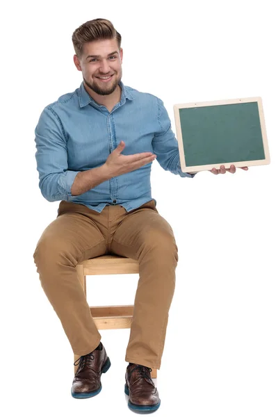 Happy young man smiling and presenting blackboard — 图库照片