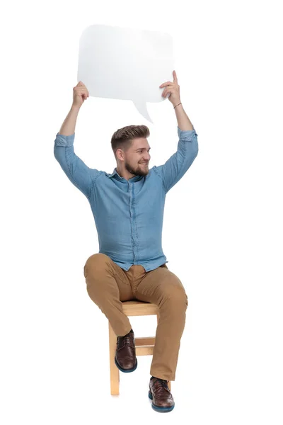 Excited young man holding speech bubble above head — Stockfoto