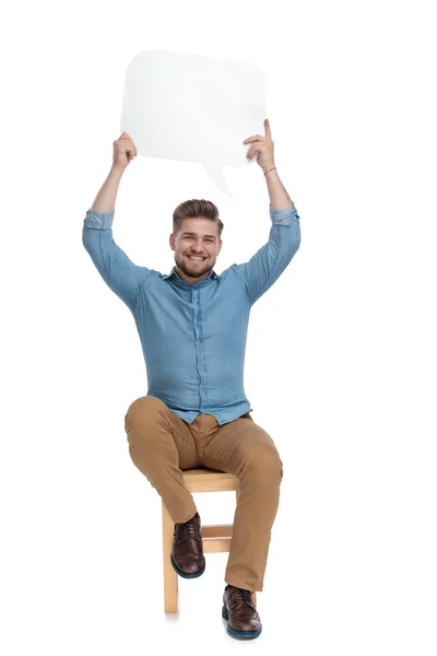 Happy young man holding speech bubble above head — Stock fotografie