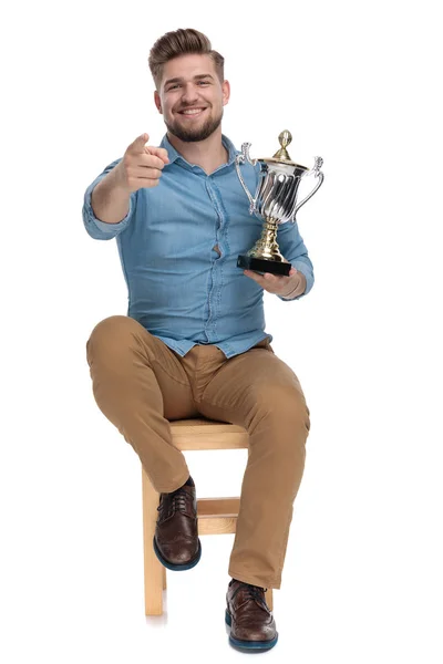 Улыбающийся молодой человек показывает пальцем и держит трофей — стоковое фото