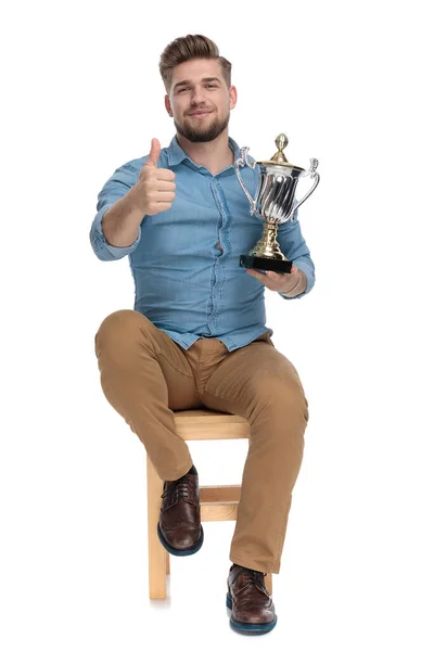 Happy young man making thumbs up sign and holding trophy — Stock Photo, Image