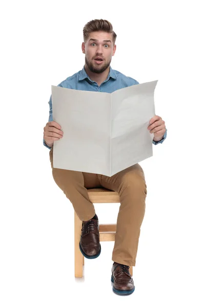 Shocked young man in denim shirt reading newspaper — 스톡 사진