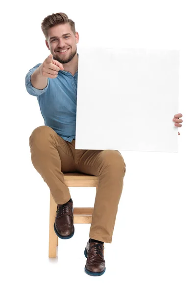 Happy young model holding empty board and pointing finger Royalty Free Stock Images