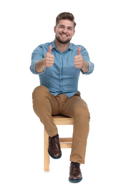 Счастливый случайный человек в джинсовой рубашке улыбается и делает большие пальцы вверх. — стоковое фото