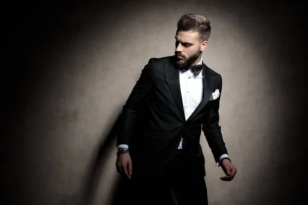Sexy elegant guy in tuxedo posing in a fashion light — Stock fotografie