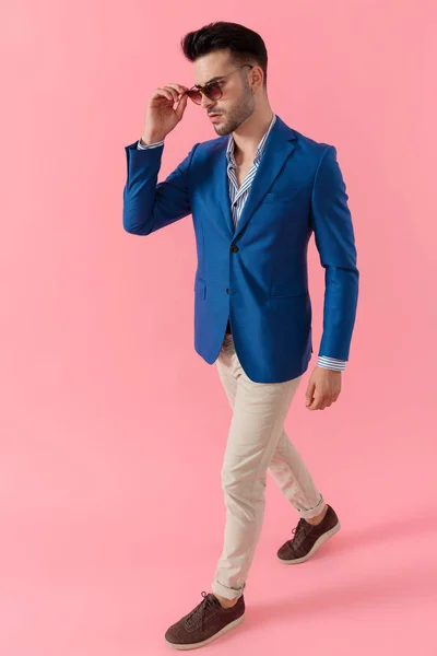 Modelo jovem sexy fixando óculos e andando sobre fundo rosa — Fotografia de Stock