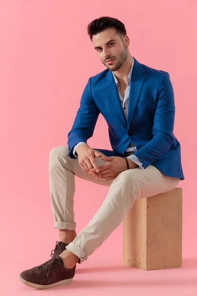 Sexy young smart casual model sitting on a wooden box — Stock fotografie