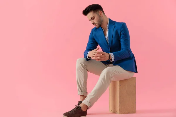 Sexy young smart casual man sitting on a wooden box — ストック写真