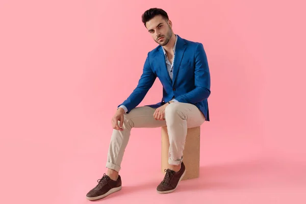 Sexy smart casual guy holding elbow on knee in a fashion pose — Stock Fotó