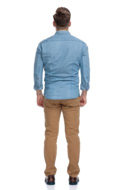 Beyaz stüdyo arka planında duran kendinden emin bir adamın arka görünüşü.