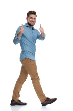 Beyaz stüdyo arka planında yürürken iki eliyle hareket eden pozitif bir adamın yan görüntüsü.