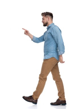 Beyaz atölyenin arka planında yürürken gülümseyen rahat bir adamın yan görüntüsü.