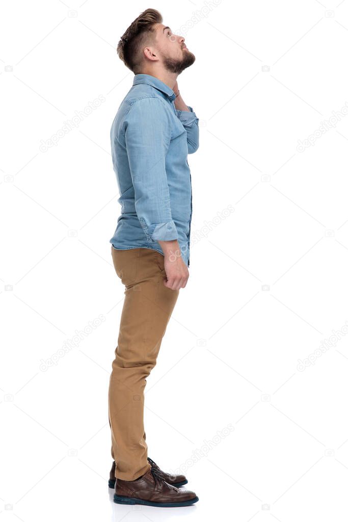 Side view of a motivated casual man looking up, standing on white studio background