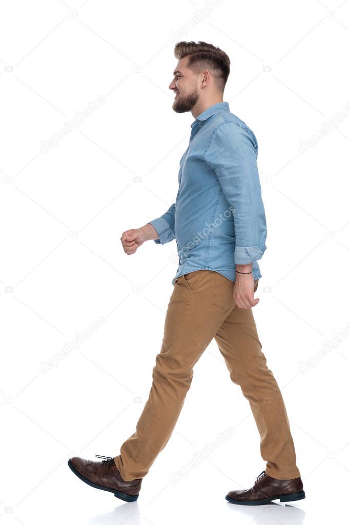 Side view of a happy casual man walking on white studio background