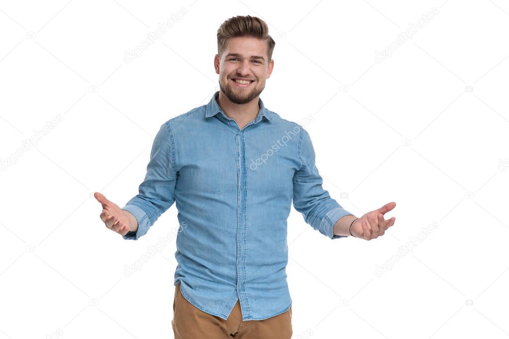 Cheerful casual man laughing and inviting, standing on white studio background