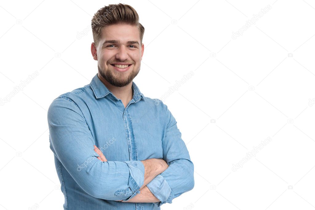 Happy casual man smiling and holding his hand crossed at his chest, standing on white studio background