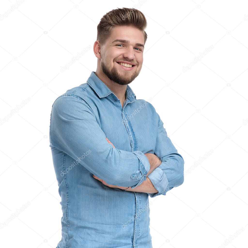 Positive casual man holding his hand crossed and smiling, standing on white studio background