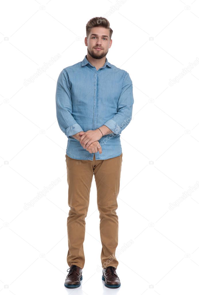 Focused casual man looking forward and listening while standing on white studio background