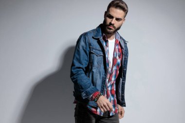 Motive olmuş manken gri stüdyo arka planında dikilirken kaşlarını çatıp başka tarafa bakıyor.