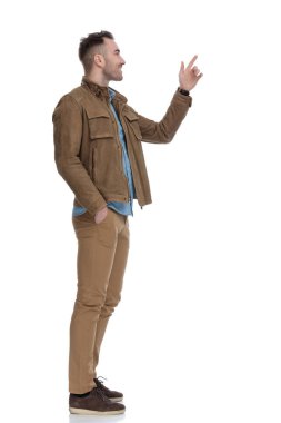 Deri ceket giyerken ve beyaz stüdyo arka planında dururken gülümseyen neşeli, sıradan bir adamın yan görüntüsü.