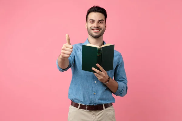 Young Casual Guy Holding Book Making Thumbs Sign Standing Pink — Stock Photo, Image