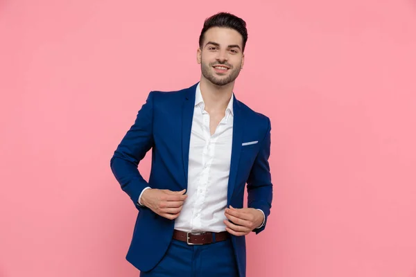 Joven Hombre Negocios Ajustando Chaqueta Sonriendo Mientras Usa Traje Azul — Foto de Stock