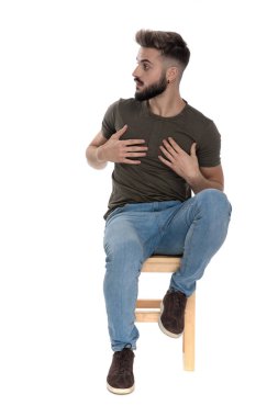 Genç, sıradan bir adam beyaz stüdyo arka planında bir sandalyede otururken şaşırdığını belirtiyor.