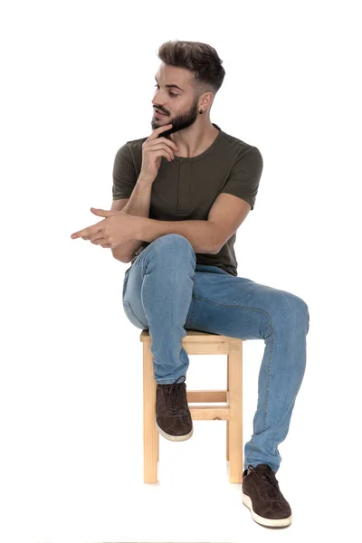 若いカジュアルな男笑顔と握手のために到達しながら 白いスタジオの背景に椅子に座って — ストック写真