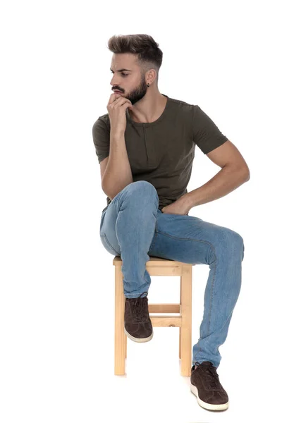 Zamyšlený Ležérní Muž Mračí Rukou Bradě Zatímco Sedí Židli Bílém — Stock fotografie