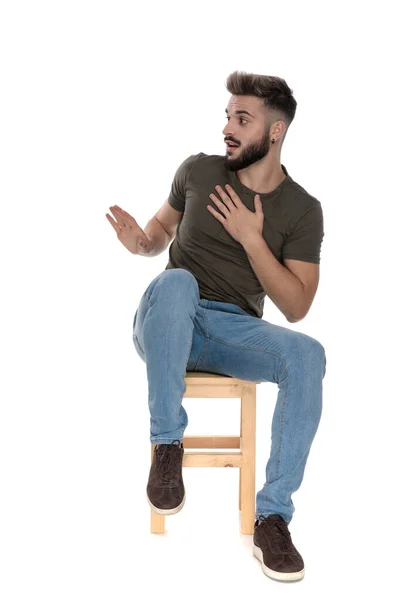 Surpreendido Casual Homem Desculpar Enquanto Sentado Uma Cadeira Fundo Estúdio — Fotografia de Stock