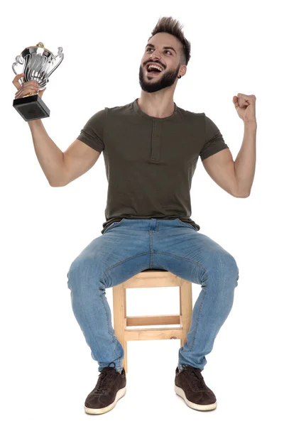 Homem Casual Vitorioso Segurando Troféu Gritando Enquanto Sentado Uma Cadeira — Fotografia de Stock