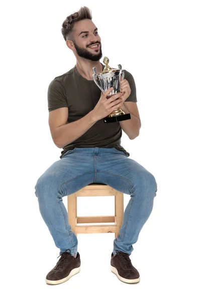 Veselý Ležérní Muž Drží Trofej Usmívá Zatímco Sedí Židli Bílém — Stock fotografie