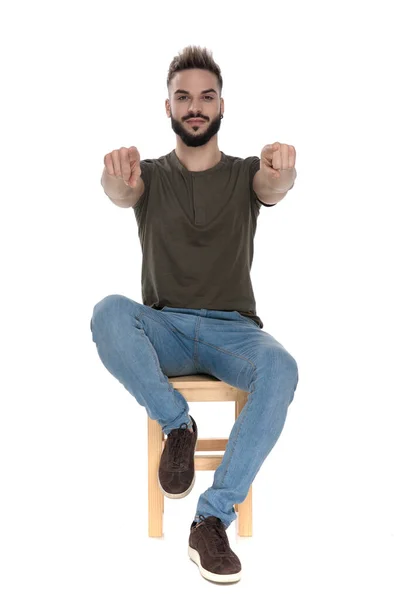 真剣なカジュアル男Pointing前方に両手で椅子に座っている間にホワイトスタジオの背景 — ストック写真