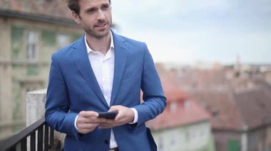 Deniz kuvvetleri kıyafeti giyen genç bir işadamı gözlerini kaçırırken telefonuna mesaj yazıyor ve merdivenlerin yanındaki korkuluklarda mutlu bir şekilde dinlenirken telefonla konuşuyor.
