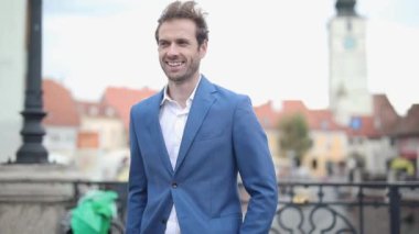 Deniz kuvvetleri kıyafeti giyen seksi iş adamı, havalı bir tavır sergiliyor, elleri cebinde ve şehrin dışında mutlu mesut etrafa bakıyor.