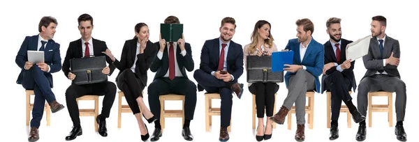 由9名商人组成的团队在等待求职面试时 坐在白色工作室背景的椅子上 一边看书 一边聊天 一边闲聊 — 图库照片
