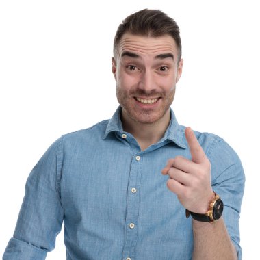 Neşeli, gülen, mavi tişörtlü, beyaz stüdyo arka planında duran, ileri bakan sıradan bir adam.