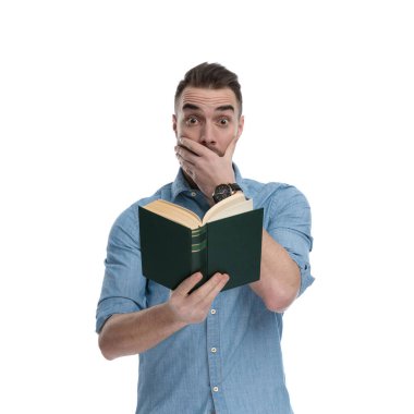 Mavi tişört giyerken, beyaz stüdyo arka planında dururken kitap okumak ve nefes nefese kalmak hayret verici.