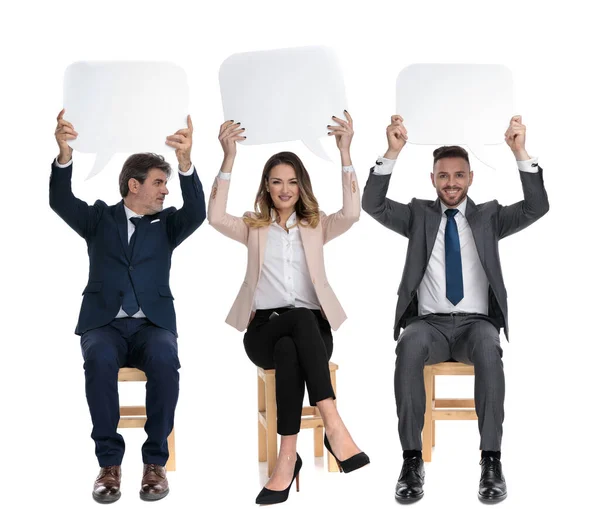 Trzech Biznesmenów Trzymających Bańkę Mowy Nad Głowami Siedząc Krzesłach Białym — Zdjęcie stockowe