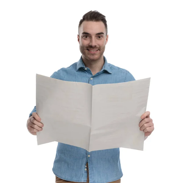 身穿蓝色衬衫 站在白色摄影棚背景上 拿着报纸 面带微笑的积极而随意的男人 — 图库照片