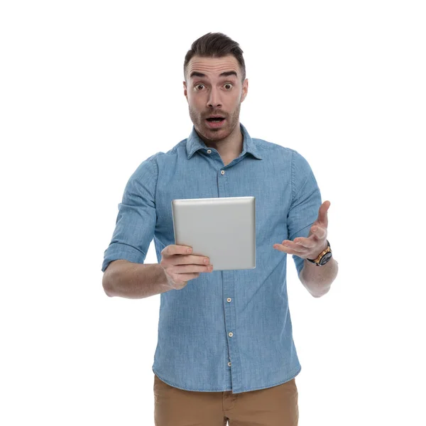 身穿蓝色衬衫 站在白色工作室背景上 拿着平板电脑 喘息的漫不经心男子 — 图库照片