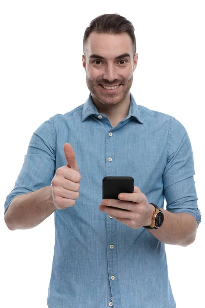 Pozytywny Swobodny Mężczyzna Trzymający Telefon Uśmiechnięty Dający Kciuki Niebieskiej Koszuli — Zdjęcie stockowe