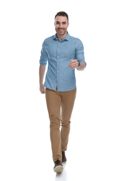 青いシャツを着て 白いスタジオの背景を歩いている間に陽気なカジュアルな男が笑っている — ストック写真