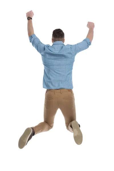 庆祝休闲人在白色工作室背景下穿着蓝色衬衫跳起来的背景图 — 图库照片